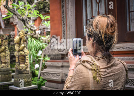 BALI, Indonesien - Januar 12, 2018: Frau nimmt Bild mit einem Smartphone im Freien auf Bali, Indonesien Stockfoto