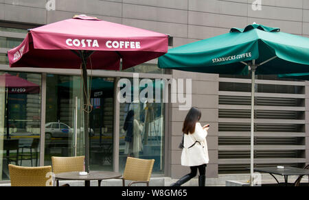 ---- Ein Fußgänger geht vorbei an Cafés von Costa Kaffee und Kaffee von Starbucks am Bund in Shanghai, China, 26. Dezember 2013. Wenn Starbucks eröffnet es Stockfoto