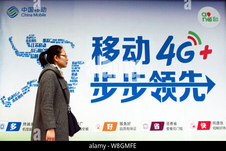 ---- Einen Fußgänger an einer Werbung Namensschild für 4G-Dienste von China Mobile in Nanjing, Provinz Jiangsu, China 29. November Stockfoto