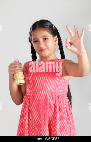 Mädchen hält eine Milchflasche und zeigt ok Sign. Stockfoto
