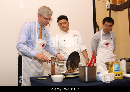 Kanadische Botschafter in China Kerl Saint-Jacques, Links, zeigt seine Kochkünste als Barry Zhu Pengcheng, rechts, Chief Merchandising Officer von yihao Stockfoto