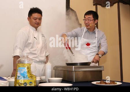 Barry Zhu Pengcheng, rechts, Chief Merchandising Officer von Yihaodian.com, seine Kochkünste während der Pressekonferenz für einen strategischen Coo Stockfoto