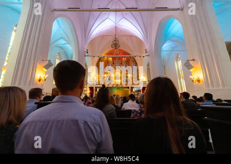 Orgel Konzert in der Kathedrale. Männer, Frauen und andere Hörer hören Musik des Komponisten. Aufregend klingen. Stockfoto