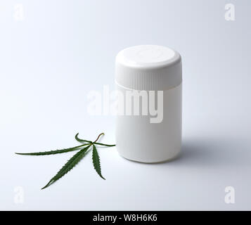 Leere Kunststoff weiß Medical jar für Pillen und grün Hanf Blatt auf einem weißen Hintergrund, alternative Medizin Konzept Stockfoto