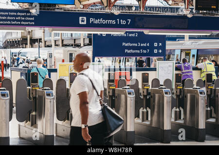 London, Großbritannien - 16 Juli, 2019: Der Mann, der hinter ticket Tore in Victoria Bahnhof, einer der belebtesten Bahnhöfen in London, UK, selektive Stockfoto