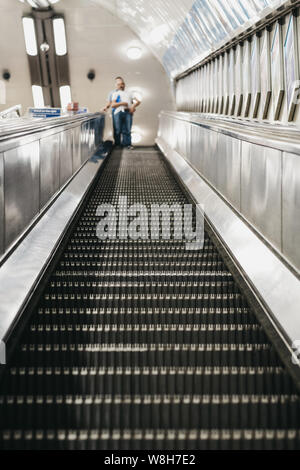 London, Großbritannien - 16 Juli, 2019: Low Angle View von Menschen auf der Rolltreppe in London Underground, der ältesten U-Bahn der Welt. Stockfoto