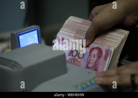 ---- Eine chinesische Angestellte verwendet eine Cash - Zählmaschine RMB (Renminbi) Yuan Banknoten bei einer Bank in der Stadt Huaibei zu zählen, der ostchinesischen Provinz Anhui, 1. Stockfoto