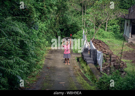 BALI, Indonesien - Januar 9, 2018: Balinesische Frau arbeitet hart an der Gewinnung von Naturstein in Bali, trägt sie mit Steinen aus dem Steinbruch auf dem Kopf Stockfoto