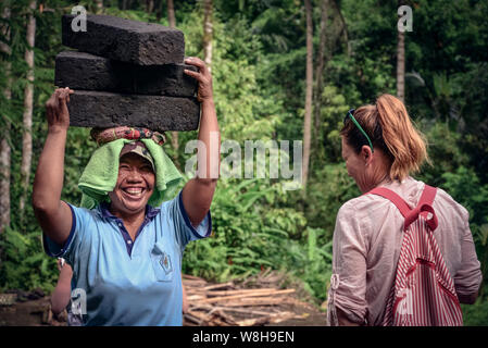 BALI, Indonesien - Januar 9, 2018: Balinesische Frau arbeitet hart an der Gewinnung von Naturstein in Bali, trägt sie mit Steinen aus dem Steinbruch auf dem Kopf Stockfoto