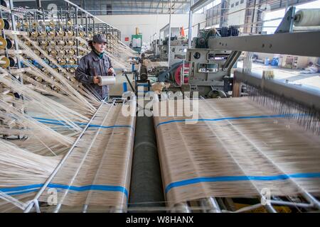 ---- Eine weibliche chinesischer Arbeiter überwacht die Herstellung von Garnen mit einer Textilfabrik in Lanzhou City, die exportiert werden sollen, der ostchinesischen Provinz Jiangsu Stockfoto