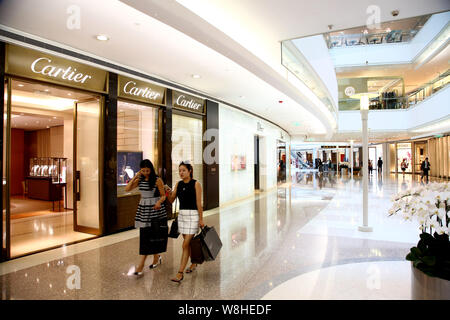 ------ Moderne, junge Frauen, die einkaufstaschen Spaziergang, vorbei an der Boutique von Cartier auf der Plaza 66 Shopping Mall in Shanghai, China, 1. September 2015 Stockfoto