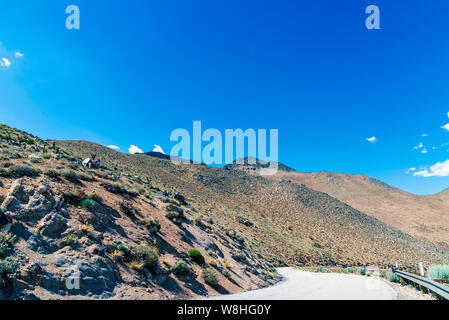 Gepflasterte Berg Straße, die Berge mit Leitplanke. Wüste felsigen Berghang unter strahlend blauen Himmel. Stockfoto