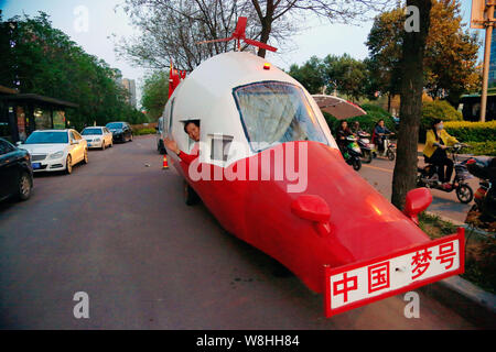 Pensionierte chinesischen Ingenieur Yuan Jingying Wellen von seinem hausgemachten Hubschrauber-förmige Fahrzeug auf einer Straße in der Stadt Zhengzhou, Provinz Henan, China Stockfoto