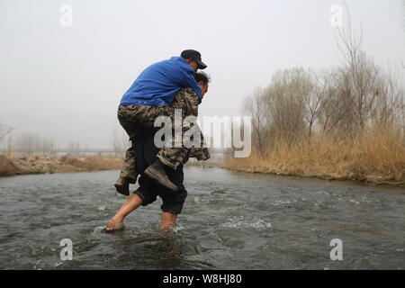 Armlose Chinese Jia Wenqi, unten, trägt seinen blinden Freund Jia Haixia auf der Rückseite, da Sie einen Fluss Bäume im Dorf Yeli zu pflanzen, Kreuz, Jingxing Stockfoto