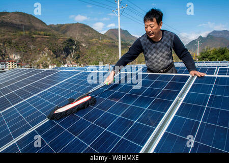 ---- Ein chinesischer Arbeiter Stäube aus Sonnenkollektoren auf dem Dach Photovoltaik- Kraftwerk in Baokang Maqiao Stadt, Grafschaft, Xiangyang City, Central China" Stockfoto