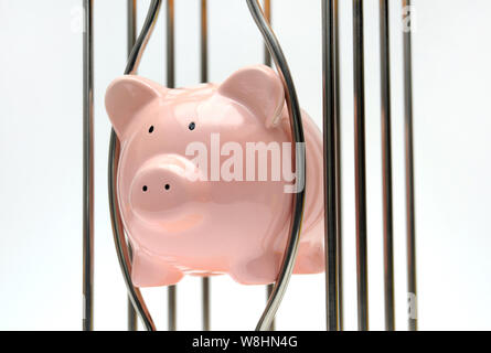 PIGGY BANK eingeklemmt zwischen KÄFIG BARS RE EINSPARUNGEN FINANZIEREN ALTERSVORSORGE ETC. UK Stockfoto