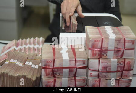 ---- Eine chinesische Angestellte verwendet eine Cash - Zählmaschine RMB (Renminbi) Yuan Banknoten bei einer Bank in der Stadt Qionghai zu zählen, der South China Hainan Provinz, Stockfoto