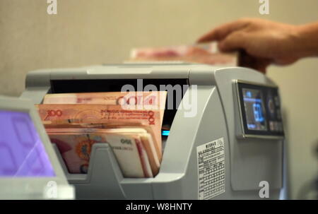 ---- Eine chinesische Angestellte verwendet eine Cash - Zählmaschine RMB (Renminbi) Yuan Banknoten bei einer Filiale der Landwirtschaftlichen Bank von China (ABC) Qiongha zu zählen Stockfoto
