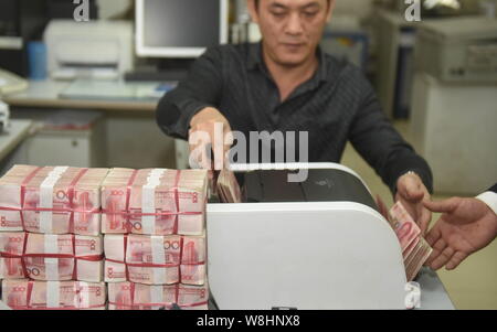 ---- Eine chinesische Angestellte verwendet eine Cash - Zählmaschine RMB (Renminbi) Yuan Banknoten bei einer Bank in der Stadt Qionghai zu zählen, South China Hainan Provinz, Stockfoto