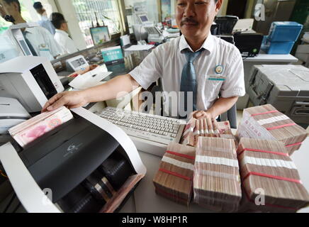 ---- Eine chinesische Angestellte verwendet eine Cash - Zählmaschine RMB (Renminbi) Yuan Banknoten bei einer Bank in der Stadt Qionghai zu zählen, der South China Hainan Provinz, Stockfoto