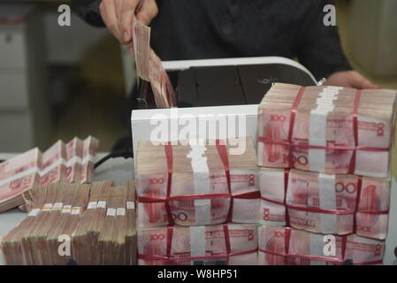 ---- Eine chinesische Angestellte verwendet eine Cash - Zählmaschine RMB (Renminbi) Yuan Banknoten bei einer Bank in der Stadt Qionghai zu zählen, South China Hainan Provinz, Stockfoto