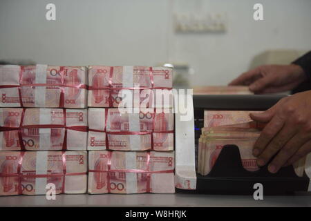 ---- Eine chinesische Angestellte verwendet eine Cash - Zählmaschine RMB (Renminbi) Yuan Banknoten bei einer Bank in der Stadt Qionghai zu zählen, South China Hainan Provinz, Stockfoto