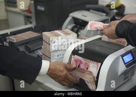 ------ Chinesische Kaufleute mit einem Cash - Zählmaschine zu zählen RMB (Renminbi) Yuan Banknoten bei einer Bank in Qionghai City, South China Hainan Provinz, 10. Stockfoto