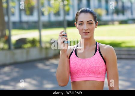 Junge Frau im Sport top Holding einen Inhalator. Stockfoto