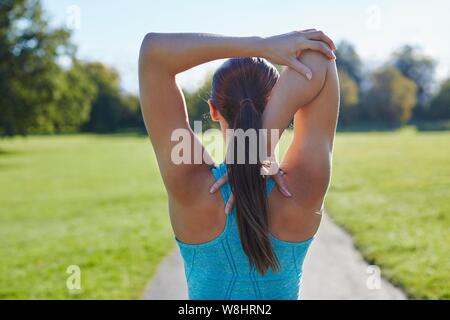 Junge Frau stretching arm, Ansicht von hinten. Stockfoto