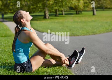 Frau trägt Trainer ihren Knöchel Holding. Stockfoto