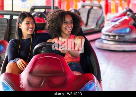 Zwei junge Frauen am Stoßfänger Auto an Kirmes. Stockfoto