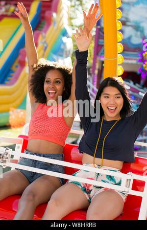 Zwei junge Frauen auf Messe Fahrt am Jahrmarkt. Stockfoto