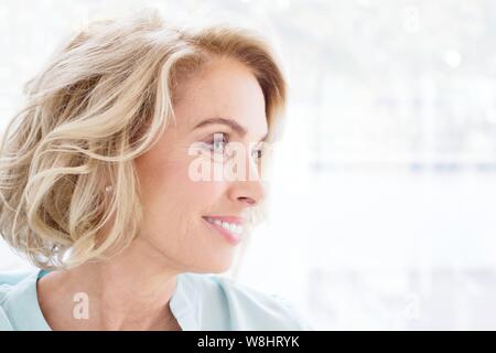 Reife Frau lächelnd und weg schauen. Stockfoto