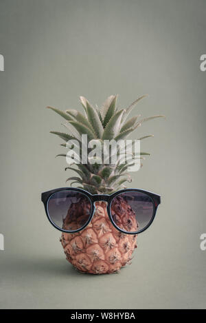 Mode hipster Ananas Obst mit Sonnenbrille auf grünem Hintergrund Stockfoto
