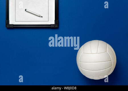 Volleyball und taktische Board mit Marker auf blauem Hintergrund. Ansicht von oben Stockfoto