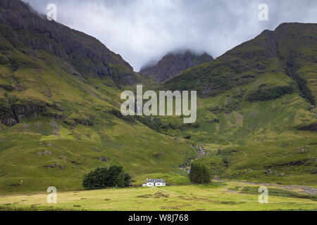 Eine malerische Landschaft von einem entfernten Haus durch ein Loch (Loch Achtriochtan) und Berge in Glencoe, die schottischen Highlands Stockfoto