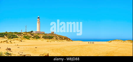 Touristen zu Fuß in Richtung Faro de Trafalgar Strand, einem breiten Strand von Cabo de Trafalgar Kap Naturpark. Conil de la Frontera, Spanien. Stockfoto