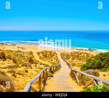 Holzsteg zum Faro de Trafalgar Strand, einem breiten Strand von Cabo de Trafalgar Kap natürlichen Park gehen. Barbate, Conil de la Frontera, Cadiz. Andalu Stockfoto