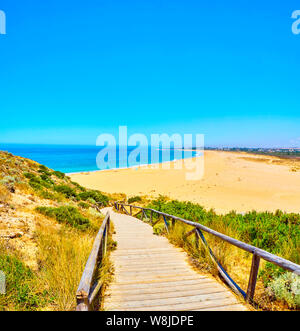 Holzsteg zum Faro de Trafalgar Strand, einem breiten Strand von Cabo de Trafalgar Kap natürlichen Park gehen. Barbate, Conil de la Frontera, Cadiz. Andalu Stockfoto