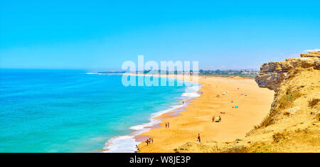 Die Menschen genießen Sie ein Sonnenbad in der Faro de Trafalgar Strand, einem breiten Strand von Cabo de Trafalgar Kap. Barbate, Spanien. Stockfoto