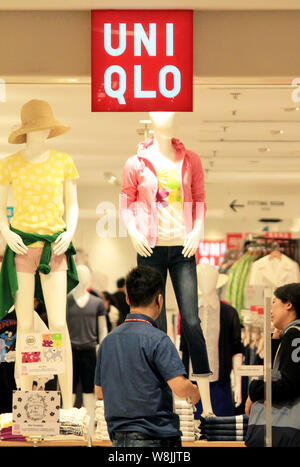 ---- Ein chinesischer Mitarbeiter mit einem Kunden im Store von Uniqlo an einem Einkaufszentrum in Nanjing, Provinz Jiangsu, China vom 23. März 2015. Stockfoto