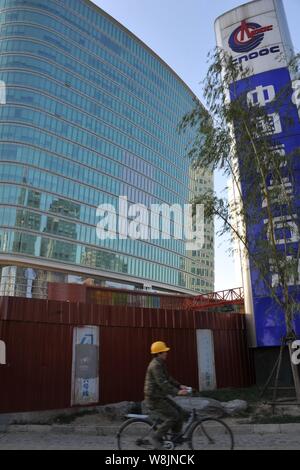 ---- Ein Radfahrer vorbei am Hauptsitz von Cnooc (China National Offshore Oil Corporation) in Peking, China, 13. November 2011. Thema Stockfoto