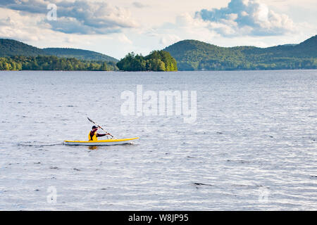 Man Paddeln ein Kajak auf See angenehm in der Nähe von Spekulant, NY USA in den Adirondack Mountains. Stockfoto