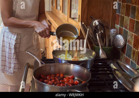 Pan mit karamellisierten Tomaten cherry Prozess des Kochens und Hinzufügen von Zutaten Hände Stockfoto