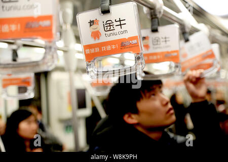 ---- Passagiere Griffe mit Werbung der Chinesischen online Reisebüro Tuniu.com in einer U-Bahn in Shanghai, China, 27. Januar 2016. Stockfoto