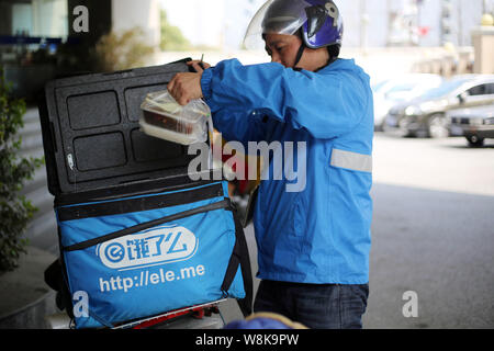 ---- Eine deliveryman der chinesischen Essen Firma Elé. Mich nimmt die Mahlzeiten aus einer Tasche auf einer Straße in Shanghai, China, 16. März geliefert werden Stockfoto