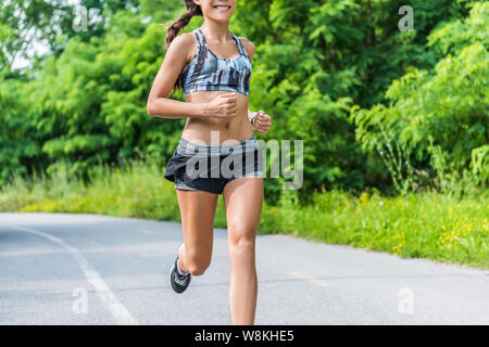 Fitness Mädchen im Sommer laufen outdoor Park. Happy fit Sportler in Sport-BH und 2-in-1-Kompression shorts Fashion activewear Outfit zeigen, schlanken Körper und ABS-Training zur Gewichtsreduktion. Stockfoto