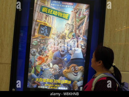 ---- Eine Chinesische filmgoer Spaziergänge hinter einem Plakat des Films 'Zootopia' in einem Kino in Kunshan City, Central China Provinz Hubei, 24. Februar 2016. Stockfoto