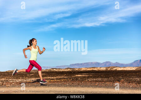 Trail Runner weiblichen Athleten in der Natur der Rocky Mountains im Hintergrund läuft. Active Fit sport Frau in Rot capris und Sportswear sprinten auf Felsen weg, cardio Training Körper. Stockfoto