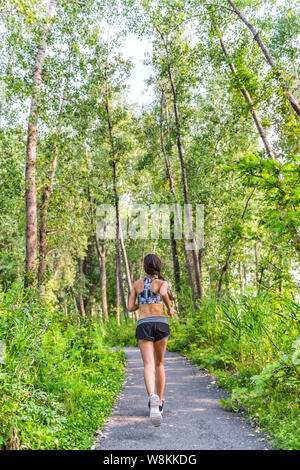 Runner Frau Training cardio auf Waldweg im Stadtpark im Sommer Natur. Zurück von Mädchen jogging leben ein gesunder aktiver Lebensstil Sport Sportbekleidung tragen Kleidung, die mit voller Länge. Stockfoto